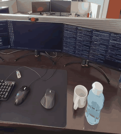 A desk with wide monitors filled with dozens of terminal panes, each one an agent session running